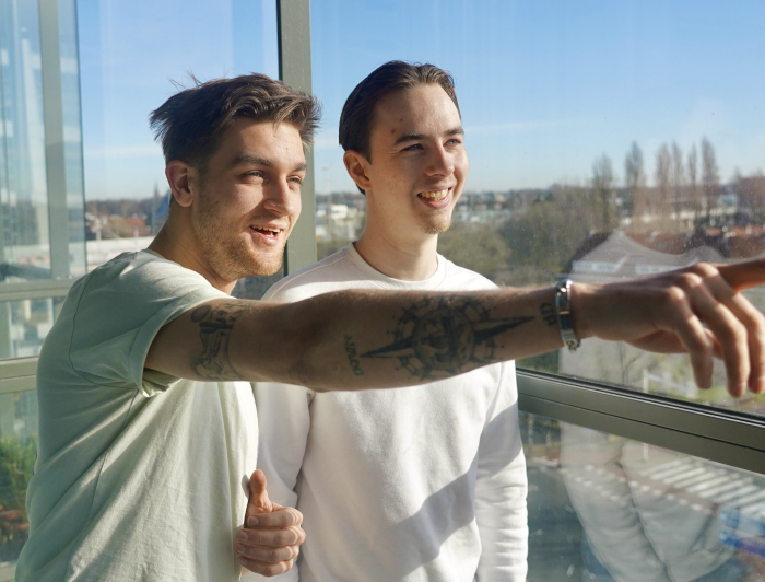 Yoshua en Rick voor het raam in hun woning aan het Maanplein