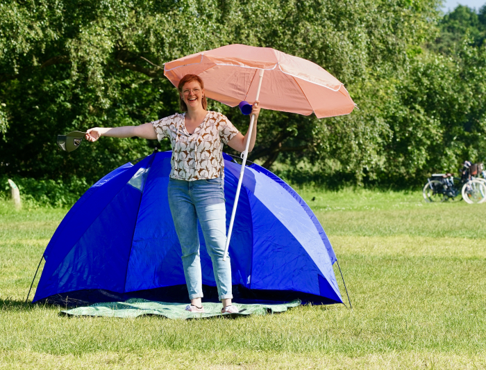 Killian voor een tent met een parasol op de Buurtcamping zuiderpark 