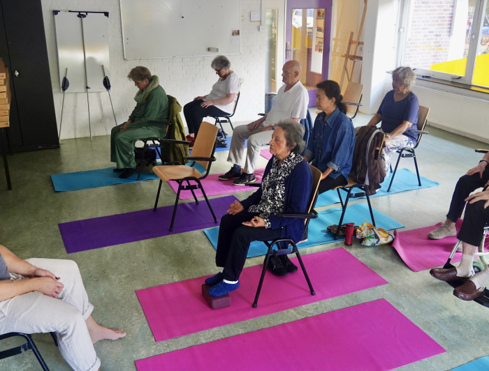 Man geeft Stoelyoga in Mariahoeve aan meerdere ouderen