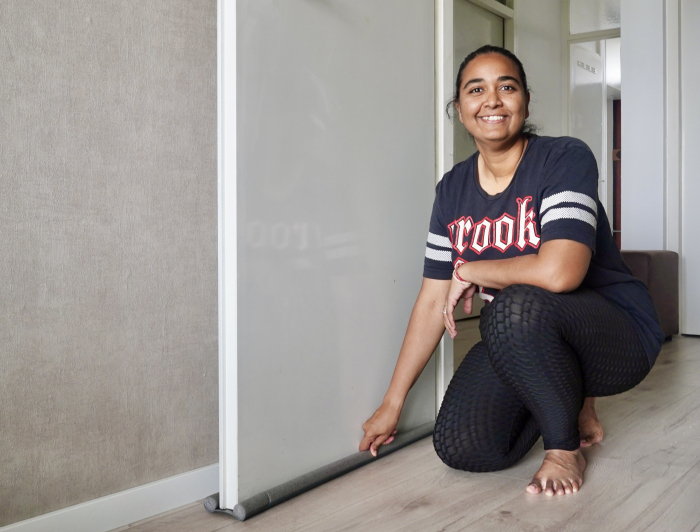 Nisha bewoner behaaglijker wonen poseert in doorgang naast de deur