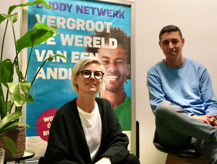 Buddy Netwerk - Ossie en Tessa zittend voor een campagneposter 