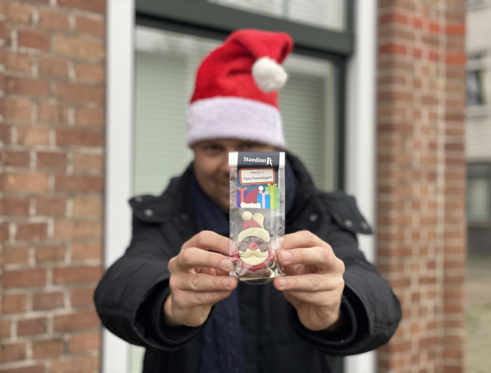 Medewerker van Staedion met kerstmuts op laat de kerstkransjes zien