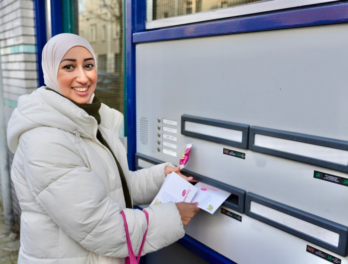 Fatima straatambassadeur doet een briefje door een brievenbus