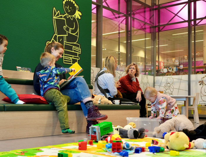 Moeders en kinderen spelen en lezen bij MIM