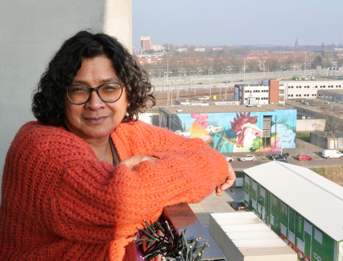 Bewoner Francine leunt over balkonreling 
