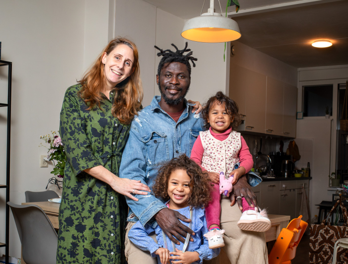 Gezin van vier personen. Vrouw, man en twee meisjes poseren in de woonkamer.