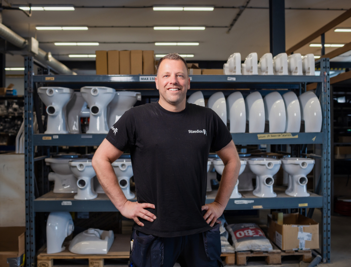 Man staat trots voor een stelling met bouwmateriaal.
