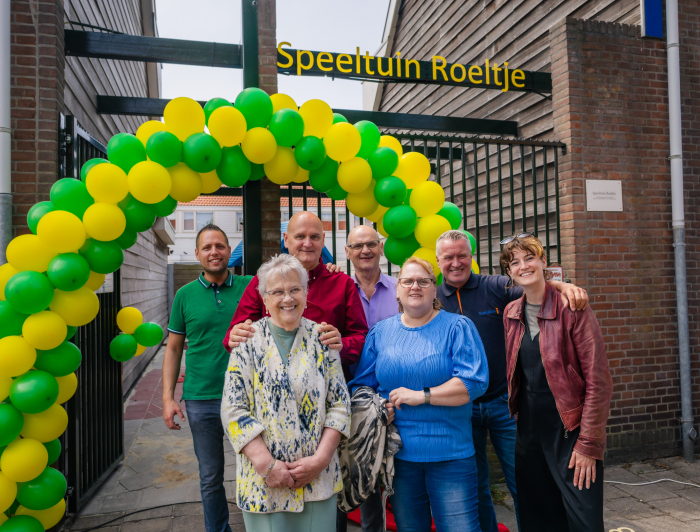Zeven mensen voor Speeltuin Roeltje, bij een boog met ballonnen. 