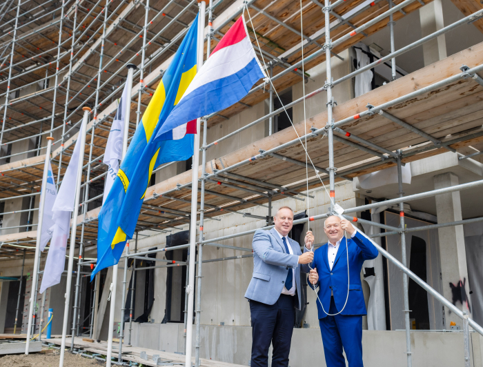 Twee mannen hijsen de Nederlandse vlag