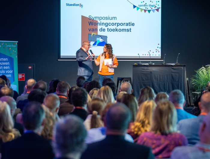 Jacques Thielen en dagvoorzitter Jessica Mendels op het podium bij het symposium Woningcorporatie van de toekomst