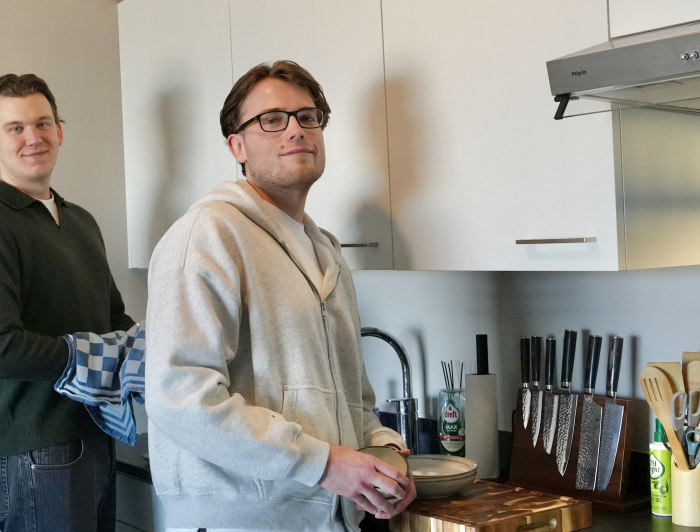 Twee vrienden aan het afwassen in de keuken.