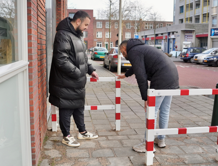 Twee mannen op straat aan het kijken naar een rood met wit hekje.