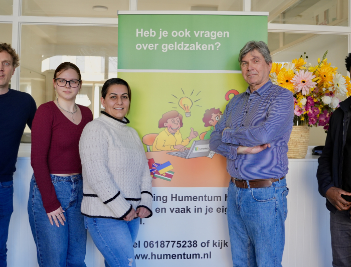 Vijf mensen van Humentum poseren bij een banner