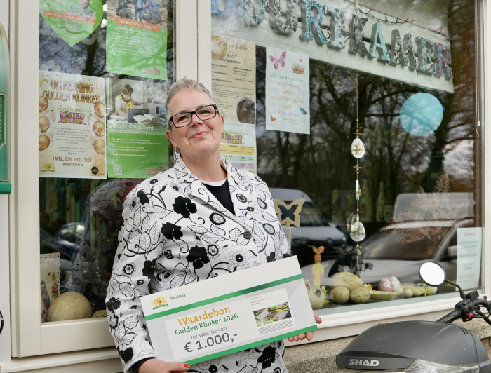Lydia poseert voor haar Buurtkamer met de cheque van de Gulden Klinker.